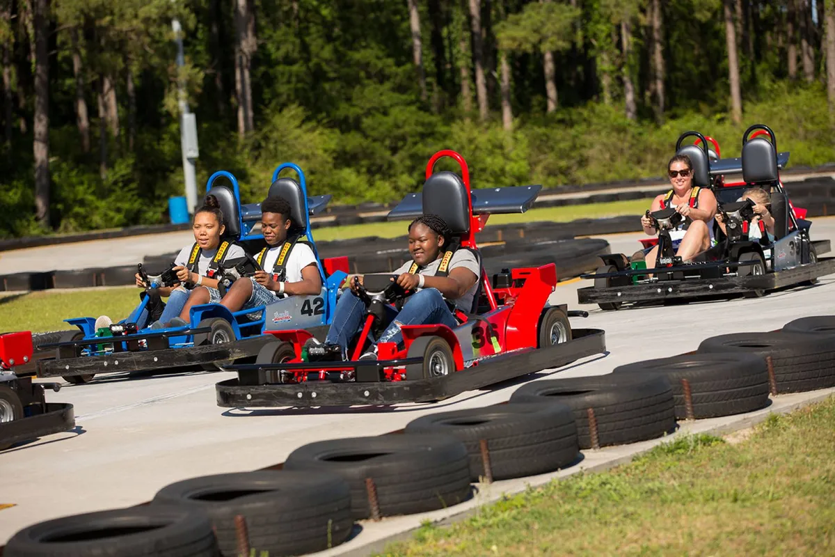 An outdoor go-kart racing track with participants engaging in friendly competition. The image highlights the fast-paced excitement and the social, group-oriented fun that comes with racing together.