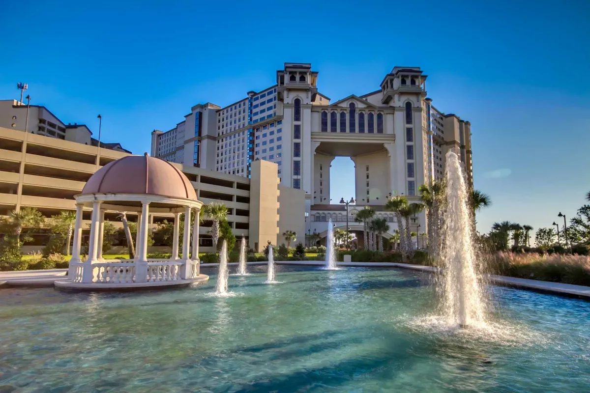 An expansive hotel exterior featuring an ornate gazebo, sparkling fountains, and lush landscaped greenery. The inviting common areas suggest opportunities for outdoor relaxation and exploration within the resort setting.